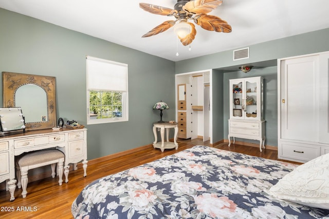 bedroom with wood finished floors, visible vents, and baseboards