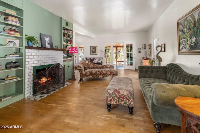 living room with wood finished floors, built in features, and a brick fireplace