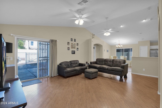 living room with ceiling fan with notable chandelier, light hardwood / wood-style floors, and vaulted ceiling