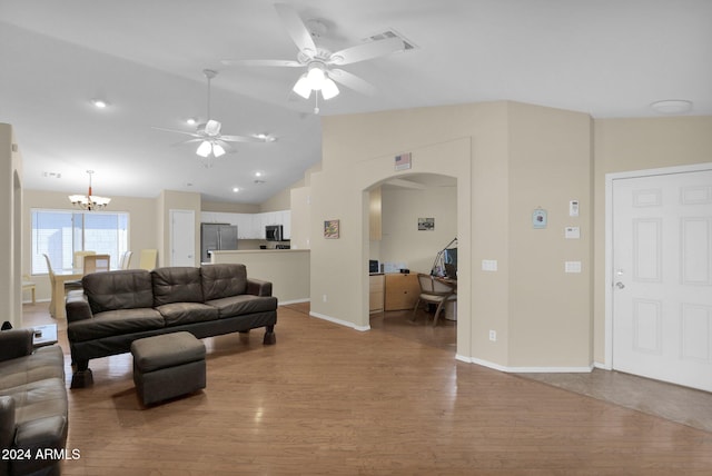 living room featuring light hardwood / wood-style floors, ceiling fan with notable chandelier, and vaulted ceiling