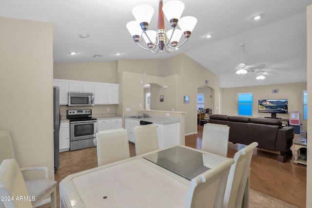 dining area featuring lofted ceiling, sink, light hardwood / wood-style floors, and ceiling fan with notable chandelier