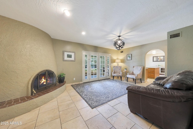6911 E Thunderbird Rd, Scottsdale, AZ 85254 - living area with a textured wall, arched walkways, french doors, and a fireplace
