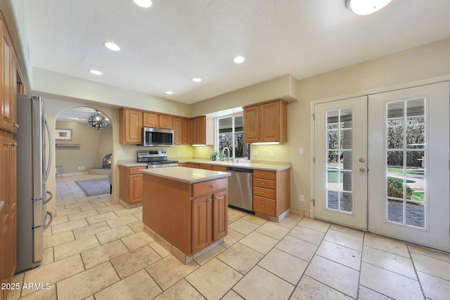 6911 E Thunderbird Rd, Scottsdale, AZ 85254 - kitchen featuring stainless steel appliances, a center island, light countertops, french doors, and arched walkways