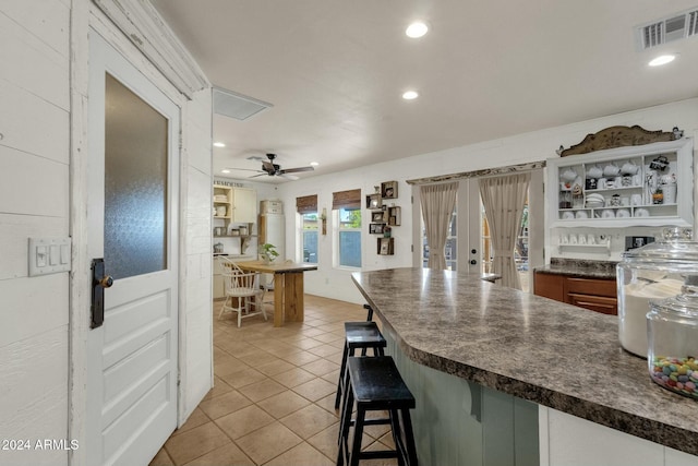 kitchen with a kitchen breakfast bar, ceiling fan, light tile patterned flooring, and french doors