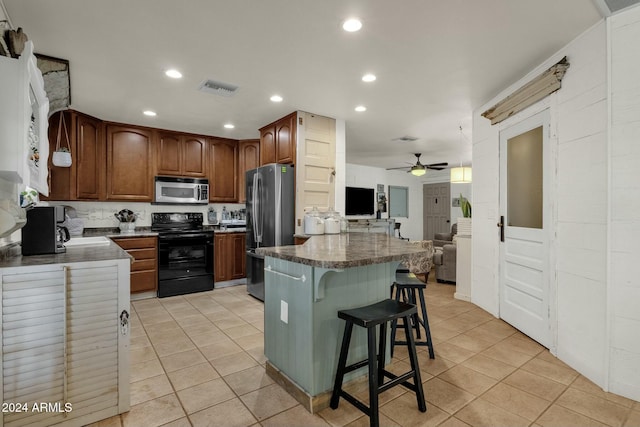 kitchen featuring appliances with stainless steel finishes, ceiling fan, a kitchen breakfast bar, and light tile patterned flooring