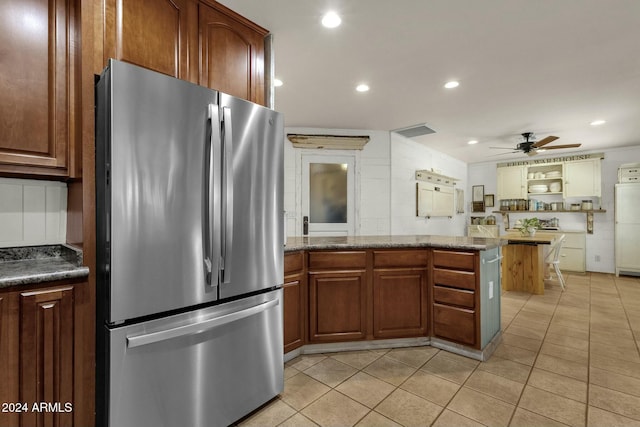 kitchen featuring kitchen peninsula, light tile patterned floors, stainless steel refrigerator, and ceiling fan