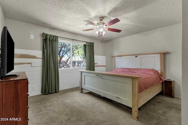 bedroom with ceiling fan, light colored carpet, and a textured ceiling