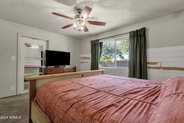 bedroom featuring carpet flooring, ceiling fan, and a textured ceiling