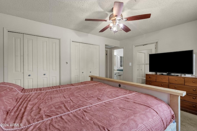 carpeted bedroom featuring ceiling fan, a textured ceiling, and two closets