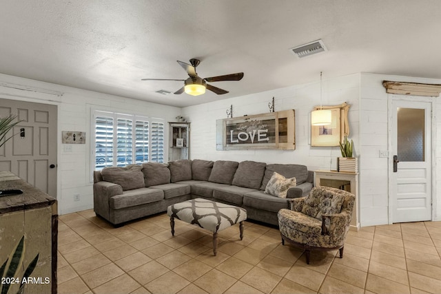 living room featuring ceiling fan, light tile patterned floors, and a textured ceiling