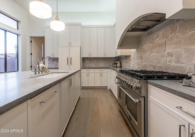 kitchen featuring sink, decorative light fixtures, white cabinetry, hardwood / wood-style flooring, and double oven range