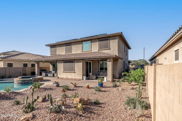 14655 W Pasadena Ave, Litchfield Park, AZ 85340 - rear view of house featuring roof mounted solar panels, a patio area, a pool with connected hot tub, a fenced backyard, and stucco siding