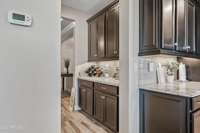 14655 W Pasadena Ave, Litchfield Park, AZ 85340 - bar featuring light wood-style flooring, baseboards, and backsplash