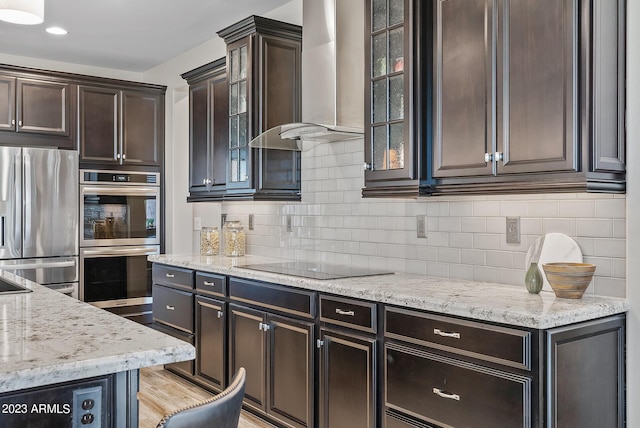14655 W Pasadena Ave, Litchfield Park, AZ 85340 - kitchen featuring wall chimney exhaust hood, light stone counters, dark brown cabinets, and appliances with stainless steel finishes