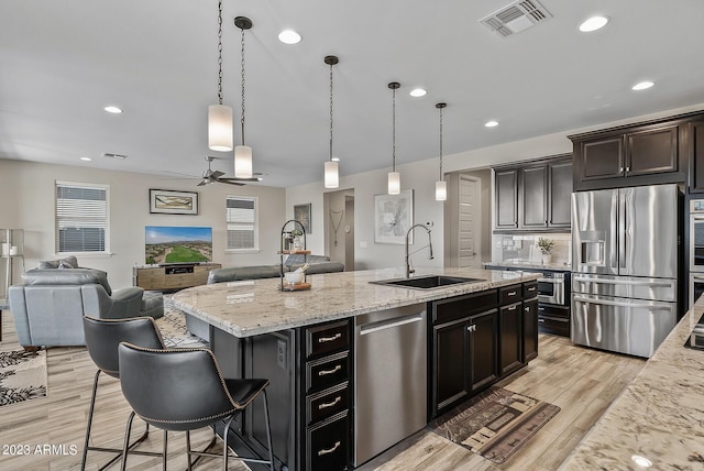 14655 W Pasadena Ave, Litchfield Park, AZ 85340 - kitchen with visible vents, a sink, a kitchen island with sink, light wood finished floors, and stainless steel appliances