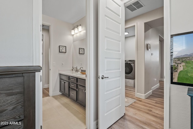 14655 W Pasadena Ave, Litchfield Park, AZ 85340 - bathroom featuring washer / clothes dryer, vanity, visible vents, wood finished floors, and baseboards