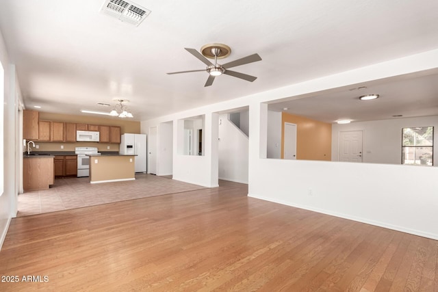 304 E Beth Dr, Phoenix, AZ 85042 - unfurnished living room featuring light wood-style flooring, ceiling fan, a sink, a chandelier, and baseboards