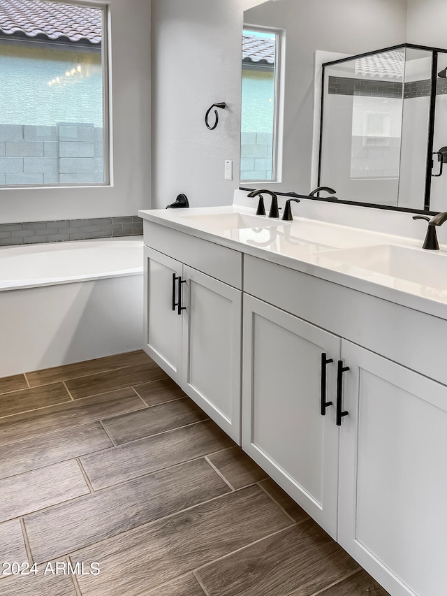 bathroom with wood-type flooring, vanity, and plus walk in shower