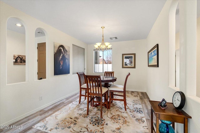 dining room featuring an inviting chandelier, baseboards, visible vents, and light wood finished floors