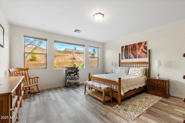 bedroom with light wood-style floors, visible vents, and baseboards