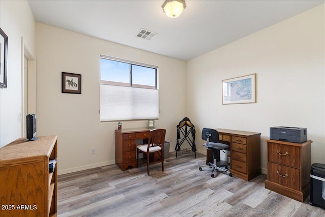 home office with light wood finished floors, visible vents, and baseboards