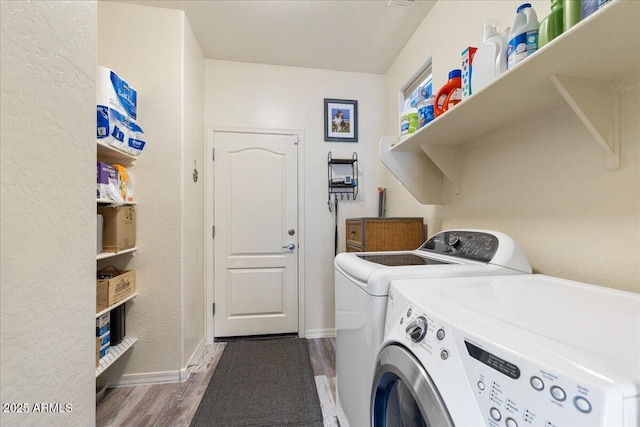 laundry area featuring wood finished floors, washing machine and dryer, baseboards, and laundry area