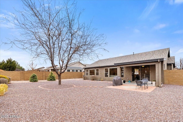 back of property with roof with shingles, a patio area, a fenced backyard, and stucco siding