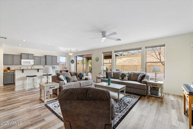 living area with visible vents, baseboards, recessed lighting, light wood-style floors, and a ceiling fan