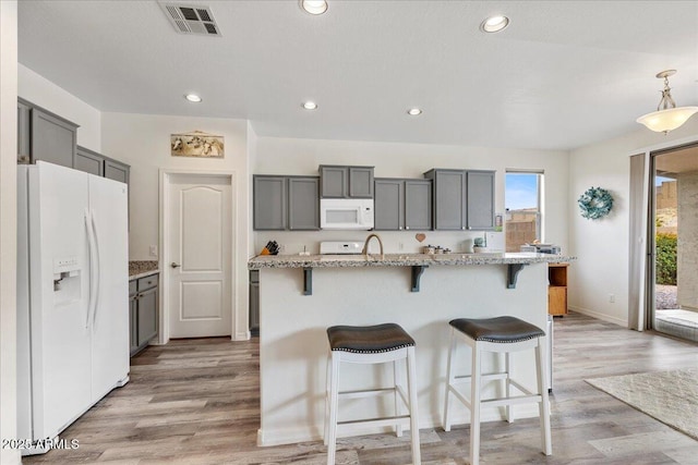 kitchen with visible vents, light wood-style flooring, white appliances, and gray cabinetry