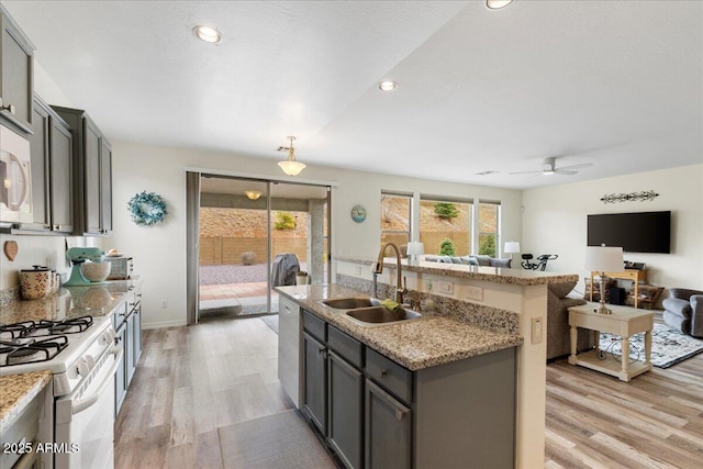 kitchen featuring white gas stove, stainless steel dishwasher, light wood-type flooring, and a sink