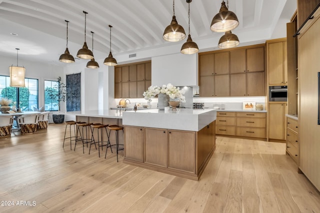 kitchen with light countertops, a spacious island, light wood-style flooring, and decorative light fixtures