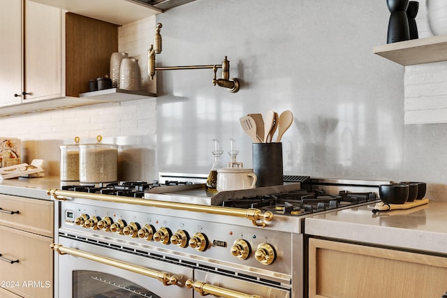 kitchen with high end stove, light countertops, light brown cabinetry, open shelves, and tasteful backsplash