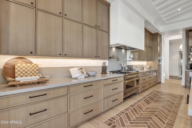 kitchen featuring light countertops, double oven range, backsplash, and light brown cabinetry