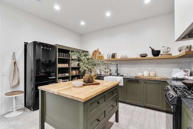 kitchen featuring green cabinets, butcher block counters, black appliances, open shelves, and a sink