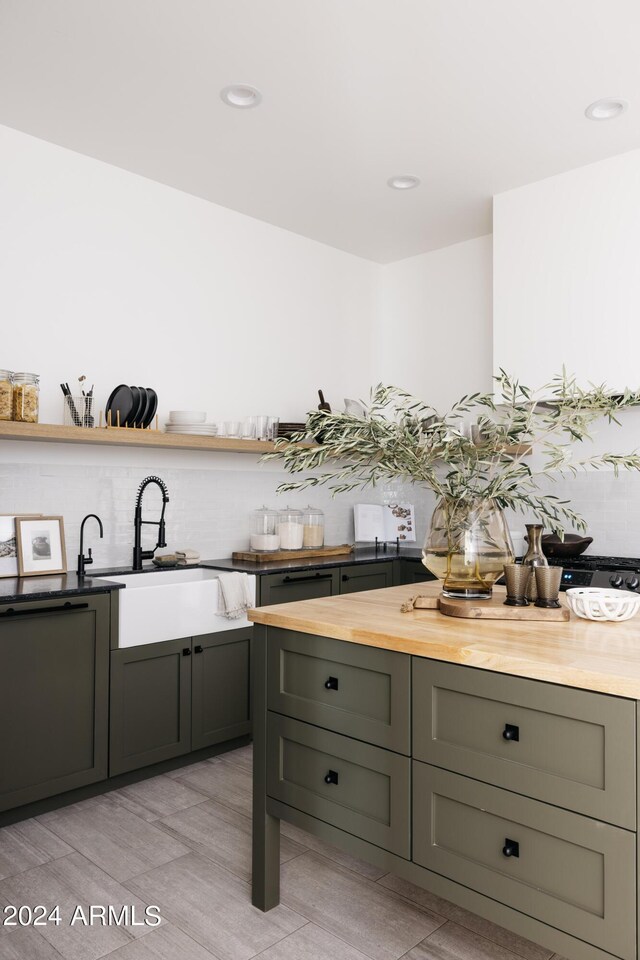 kitchen featuring butcher block countertops, sink, backsplash, and light tile patterned floors