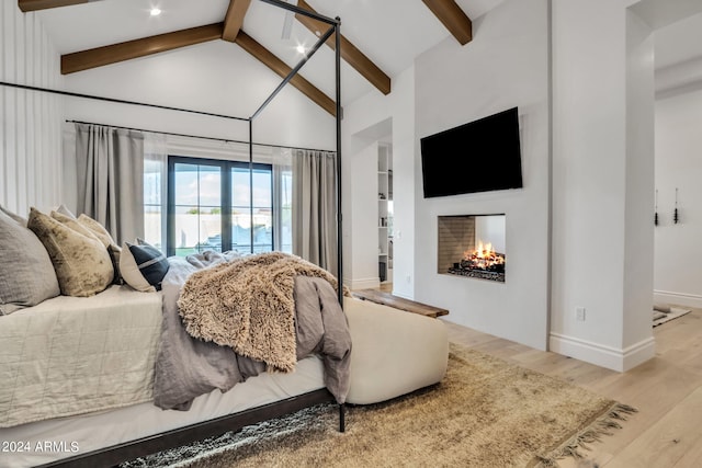 bedroom with high vaulted ceiling, beamed ceiling, and light wood-type flooring