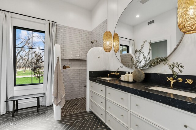 bathroom featuring dual vanity and a tile shower