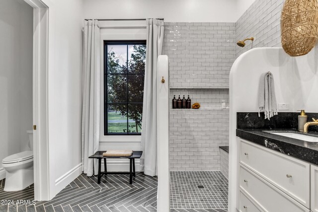 bathroom featuring tiled shower, vanity, tile patterned floors, and toilet