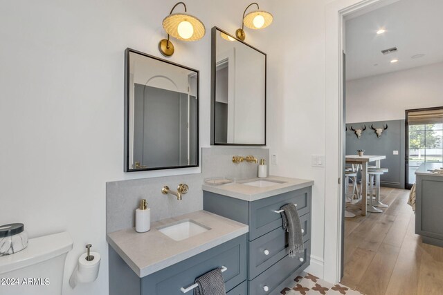 bathroom with toilet, backsplash, double sink vanity, and hardwood / wood-style floors