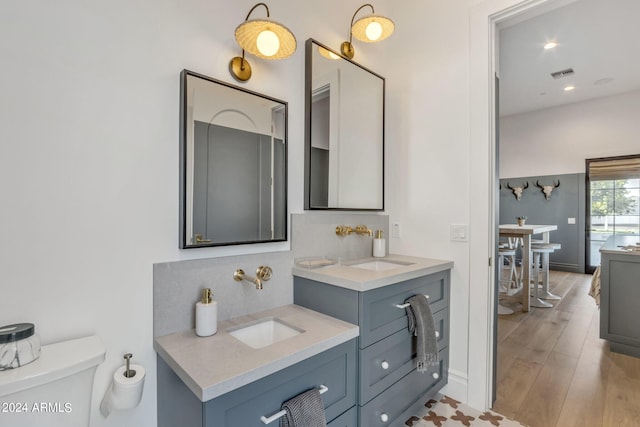 bathroom with visible vents, a sink, decorative backsplash, and wood finished floors