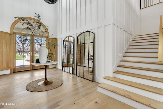 interior space with a high ceiling, stairway, arched walkways, and wood finished floors