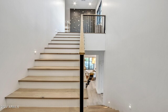 stairway featuring light hardwood / wood-style floors and a towering ceiling