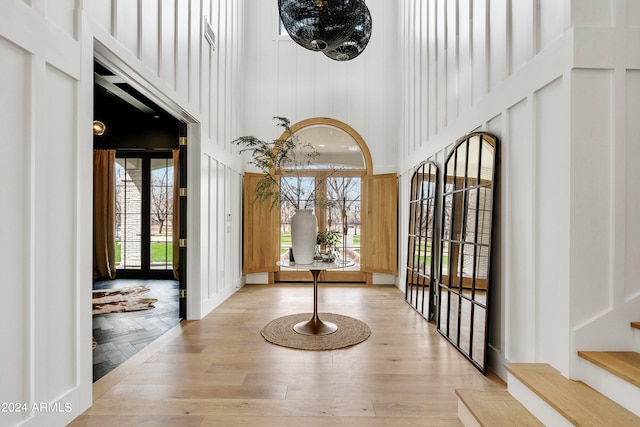 entryway featuring a healthy amount of sunlight, light hardwood / wood-style flooring, and a towering ceiling