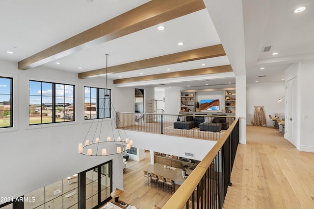 interior space with a chandelier, light wood-type flooring, decorative light fixtures, and beam ceiling