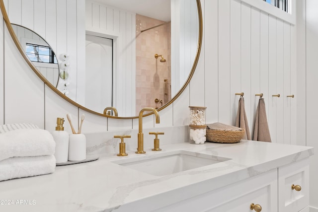 room details with wood walls, tiled shower, and vanity