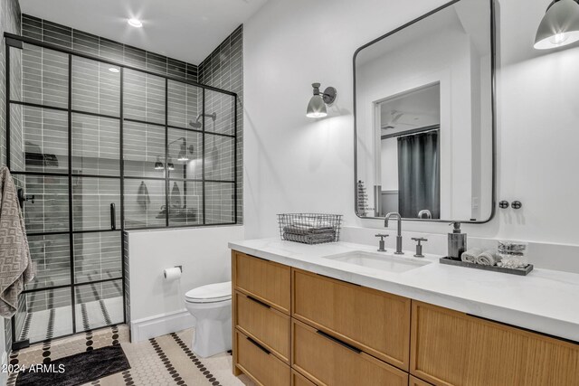 bathroom with a shower with door, vanity, tile patterned flooring, and toilet