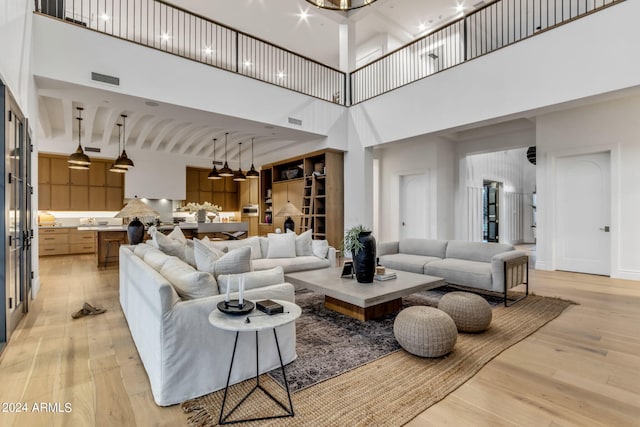 living room with visible vents, light wood-style flooring, and a towering ceiling