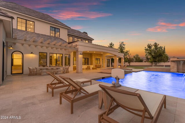 pool at dusk featuring a patio and pool water feature