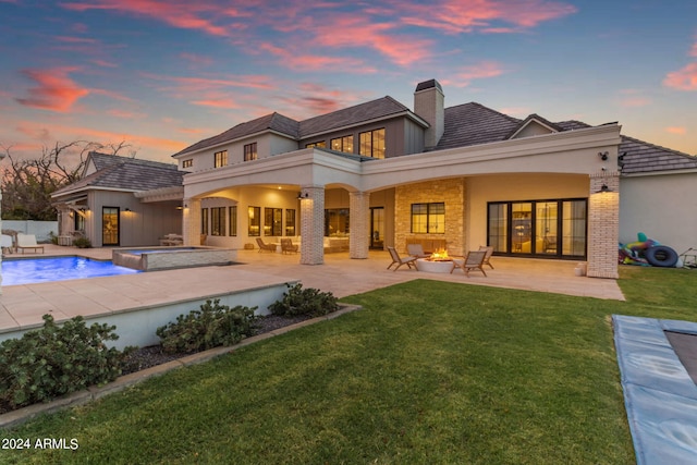 back of house at dusk featuring a fenced in pool, a patio, a chimney, an in ground hot tub, and a yard