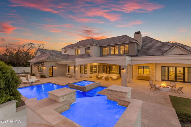 pool at dusk with a patio, an in ground hot tub, and a fire pit